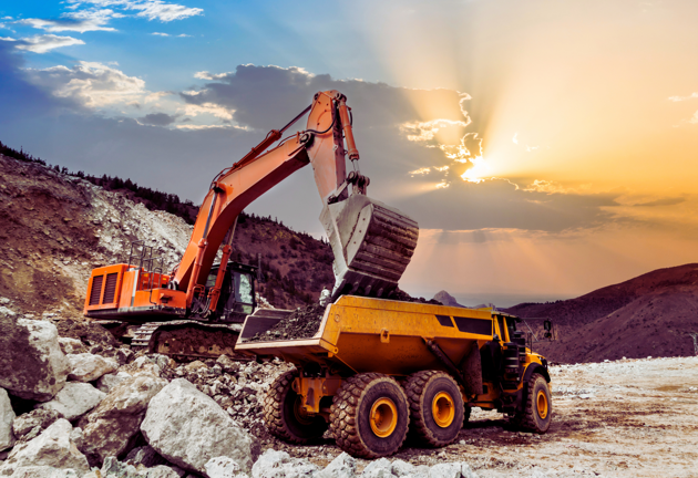 A digger in a quarry at sunset